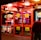 A brightly lit entrance to a casino with neon signs, including one advertising a £500 jackpot. The doors have clear signage indicating entry is restricted to those over 18. A person in a red jacket stands to the right, possibly interacting with a machine or display.